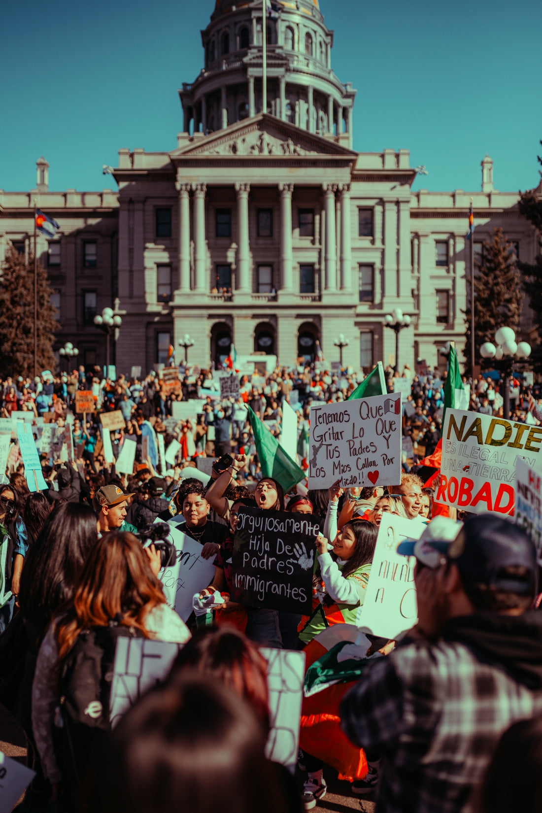 People protest with signs in front of a government building.